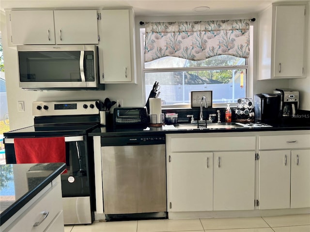 kitchen with white cabinets, sink, light tile patterned floors, and stainless steel appliances