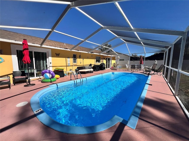 view of swimming pool featuring glass enclosure and a patio area