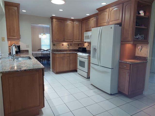 kitchen featuring white appliances, sink, dark stone countertops, a notable chandelier, and kitchen peninsula