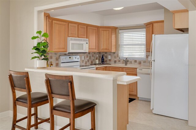 55 Harbor View Ln Unit 301, Belleair Bluffs, FL 33770 - kitchen with white appliances, a peninsula, tasteful backsplash, a kitchen bar, and light countertops