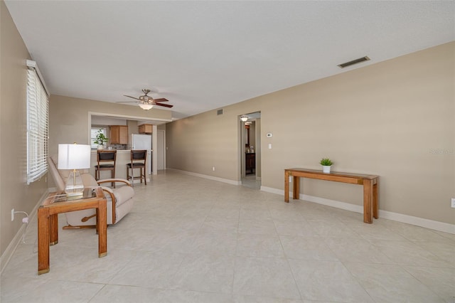 living area with ceiling fan and light tile patterned floors