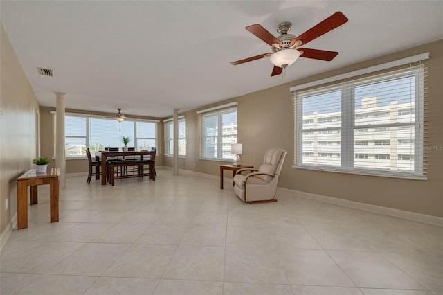 sitting room with ornate columns, ceiling fan, and light tile patterned flooring