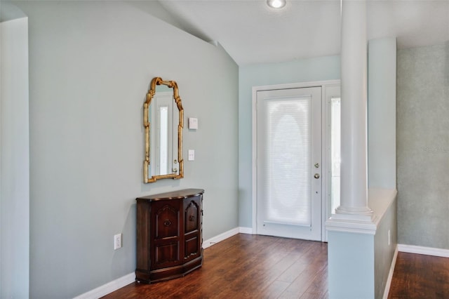 foyer featuring dark hardwood / wood-style floors, vaulted ceiling, and decorative columns