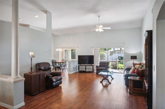 living room with decorative columns, ceiling fan, and dark hardwood / wood-style floors