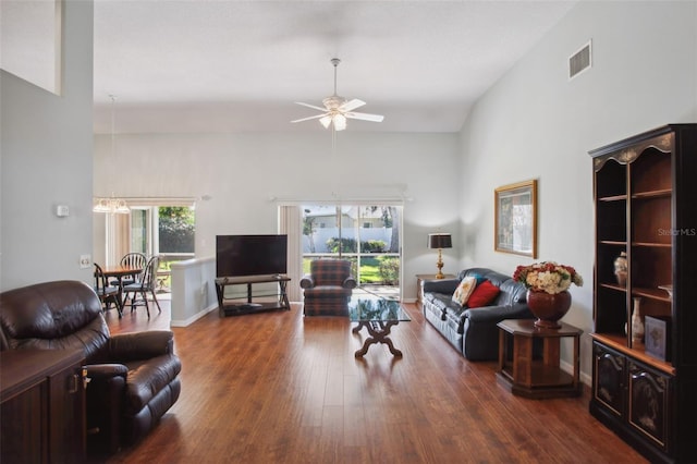 living room with ceiling fan, dark hardwood / wood-style flooring, and a towering ceiling