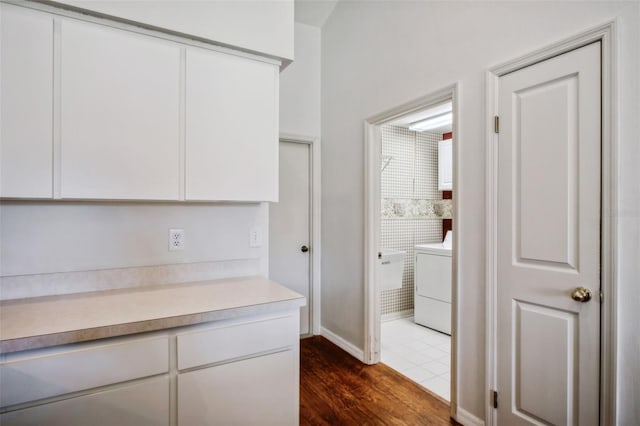 interior space with washer / clothes dryer, white cabinetry, and dark hardwood / wood-style floors