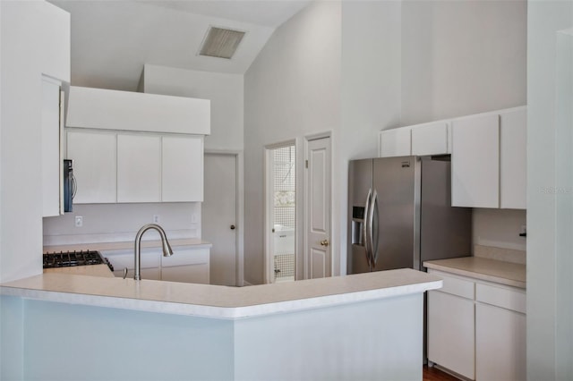 kitchen with kitchen peninsula, appliances with stainless steel finishes, high vaulted ceiling, and white cabinetry