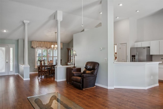 living room with dark hardwood / wood-style flooring, decorative columns, high vaulted ceiling, and a chandelier