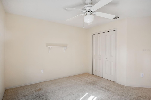 unfurnished bedroom with light colored carpet, a closet, and ceiling fan