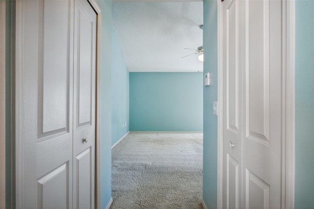 hallway with carpet flooring and a textured ceiling