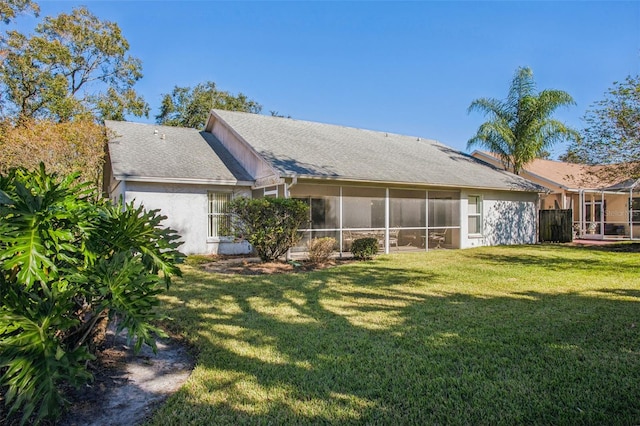 rear view of property with a lawn and a sunroom