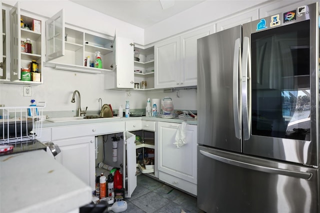 kitchen featuring dark tile patterned floors, stainless steel fridge, sink, and white cabinets