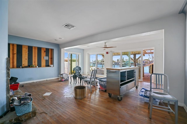 living room featuring ceiling fan, a water view, and hardwood / wood-style flooring