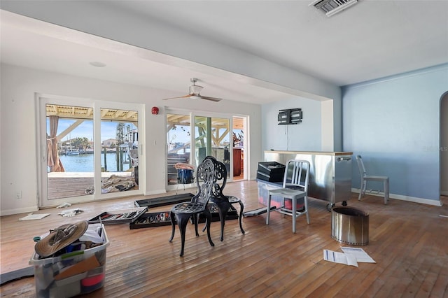 exercise area featuring plenty of natural light, ceiling fan, a water view, and wood-type flooring