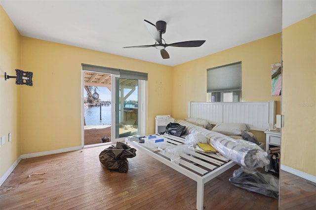 bedroom featuring access to exterior, ceiling fan, a water view, and hardwood / wood-style flooring