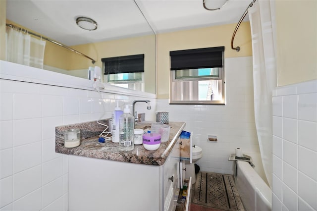 bathroom with shower / bath combo with shower curtain, vanity, tile walls, and a healthy amount of sunlight