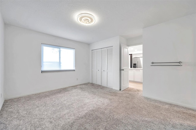 650 Island Way Unit 106, Clearwater Beach, FL 33767 - unfurnished bedroom featuring light carpet, a closet, baseboards, high end fridge, and ensuite bathroom