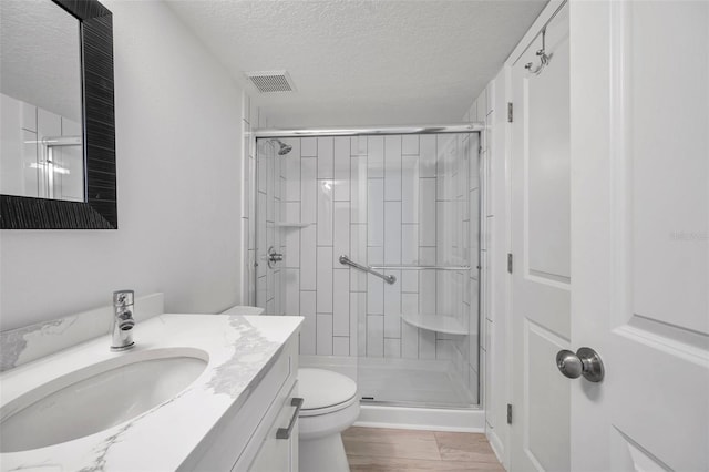 650 Island Way Unit 106, Clearwater Beach, FL 33767 - full bath featuring toilet, vanity, a stall shower, a textured ceiling, and wood finished floors