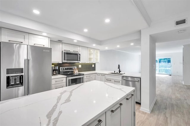 kitchen featuring a sink, stainless steel appliances, light stone counters, white cabinetry, and visible vents