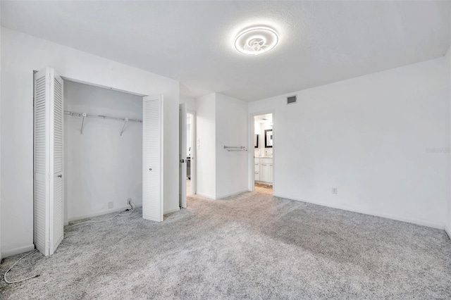 unfurnished bedroom with a closet, light colored carpet, a textured ceiling, and visible vents