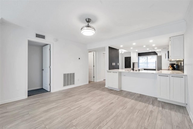 unfurnished living room with light wood finished floors, baseboards, and visible vents