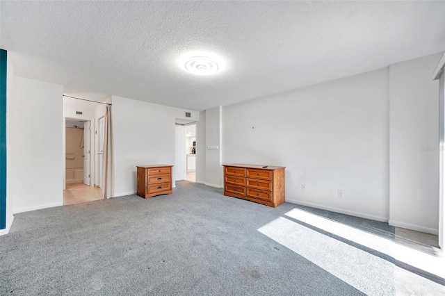 unfurnished bedroom with light carpet, baseboards, visible vents, a textured ceiling, and ensuite bathroom