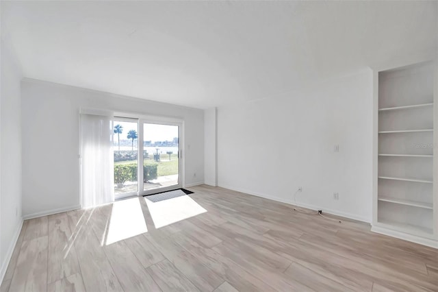 unfurnished room featuring built in features, light wood-style floors, and baseboards