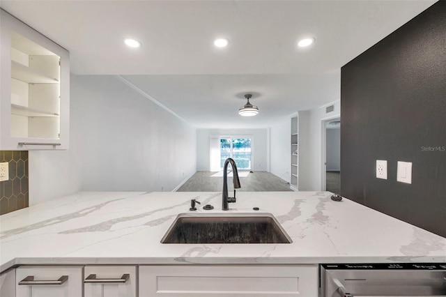 kitchen with light stone countertops, tasteful backsplash, dishwasher, white cabinetry, and a sink