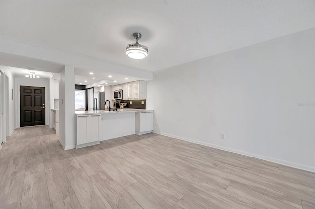 kitchen with stainless steel microwave, a peninsula, white cabinets, light countertops, and open floor plan