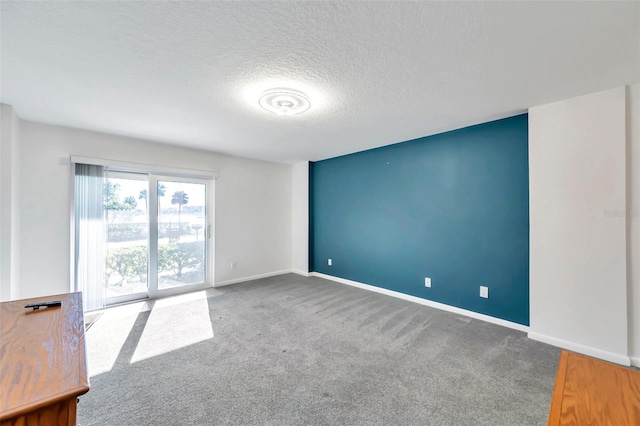 unfurnished room with a textured ceiling, carpet floors, and baseboards