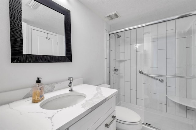 bathroom with visible vents, vanity, a shower stall, and toilet