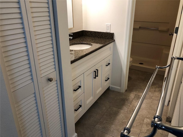 full bath with toilet, a closet, a shower stall, vanity, and stone finish flooring