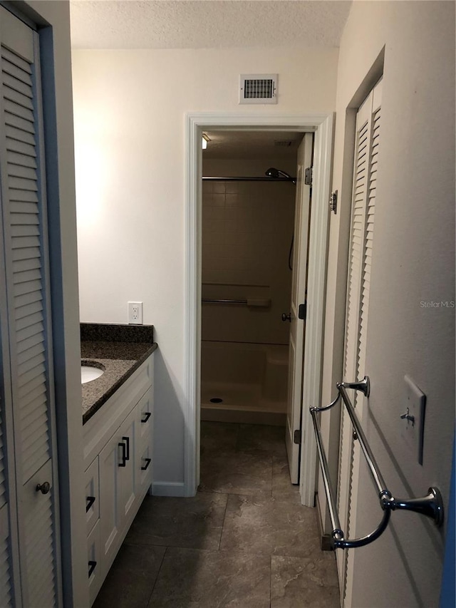 full bath featuring visible vents, a closet, a textured ceiling, and vanity