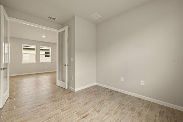 unfurnished room featuring french doors and light hardwood / wood-style flooring