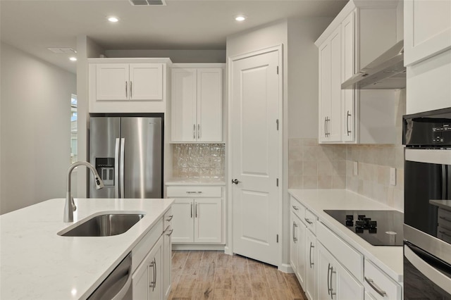 kitchen with white cabinetry, appliances with stainless steel finishes, light stone countertops, and sink