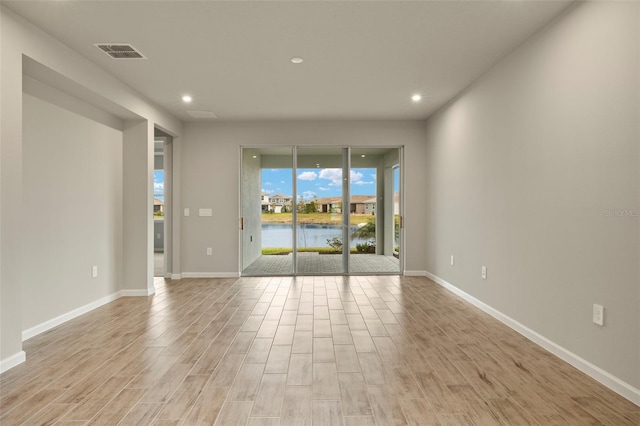 unfurnished room featuring light wood-type flooring and a water view