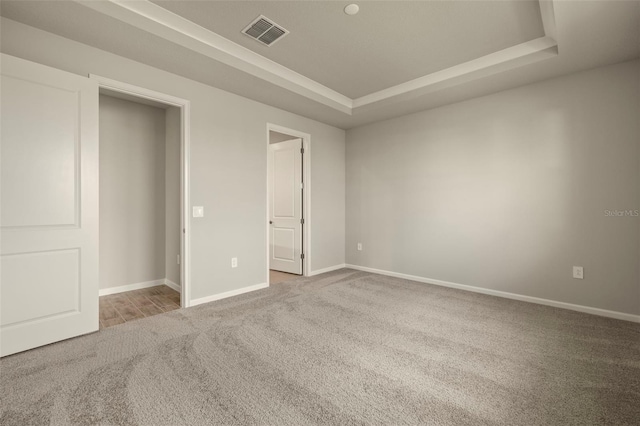 unfurnished bedroom with carpet flooring and a tray ceiling