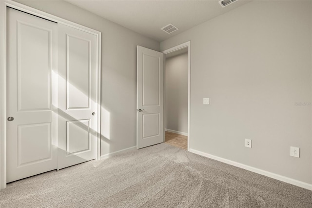 unfurnished bedroom featuring light colored carpet and a closet