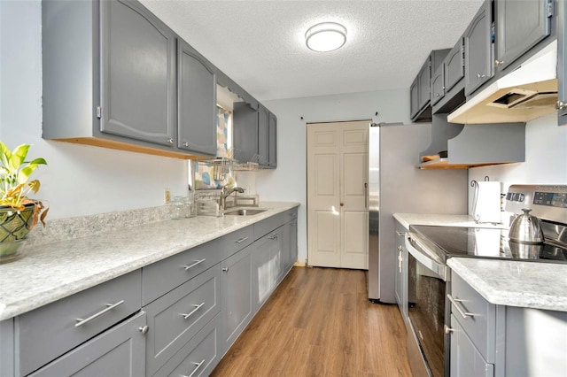 kitchen featuring gray cabinetry, electric stove, sink, light wood-type flooring, and a textured ceiling