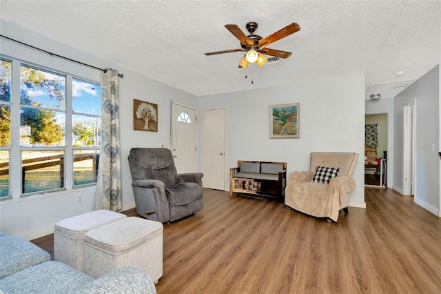 living room featuring wood-type flooring, a textured ceiling, plenty of natural light, and ceiling fan