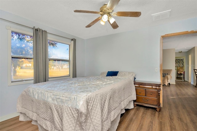 bedroom with a textured ceiling, dark hardwood / wood-style floors, and ceiling fan