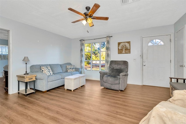 living room with a textured ceiling, light hardwood / wood-style floors, and ceiling fan