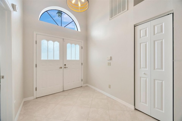 foyer entrance featuring a towering ceiling and light tile patterned flooring