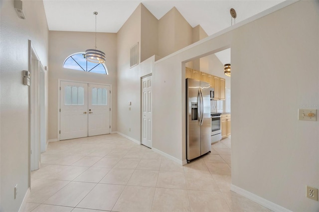 tiled entrance foyer featuring a notable chandelier and high vaulted ceiling