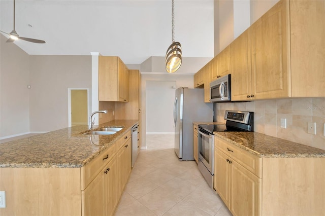 kitchen with light stone countertops, light brown cabinets, sink, decorative light fixtures, and appliances with stainless steel finishes