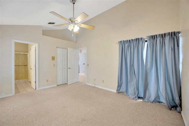 unfurnished bedroom featuring ensuite bath, light carpet, ceiling fan, and vaulted ceiling