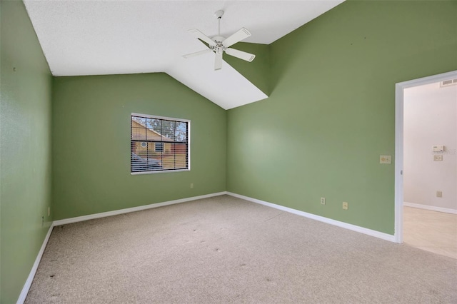 spare room with ceiling fan, light colored carpet, and vaulted ceiling