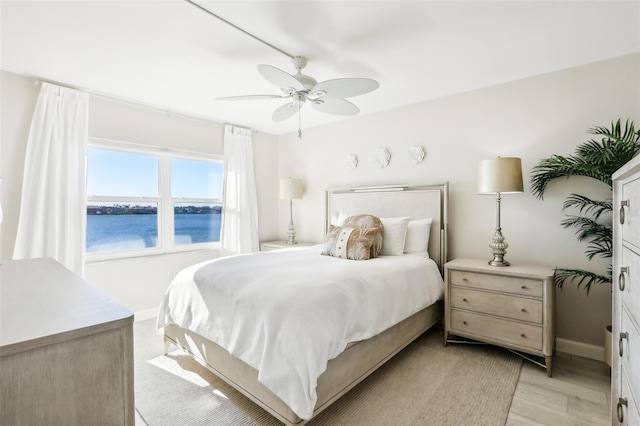 bedroom featuring a water view, ceiling fan, and light hardwood / wood-style floors