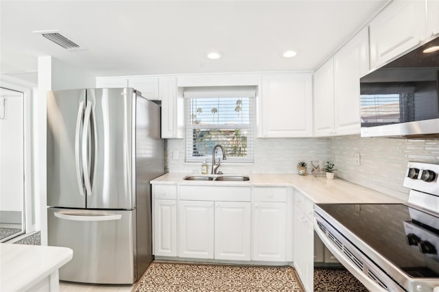 kitchen with backsplash, white cabinetry, sink, and stainless steel appliances