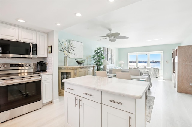 kitchen featuring decorative backsplash, white cabinetry, a center island, and stainless steel appliances